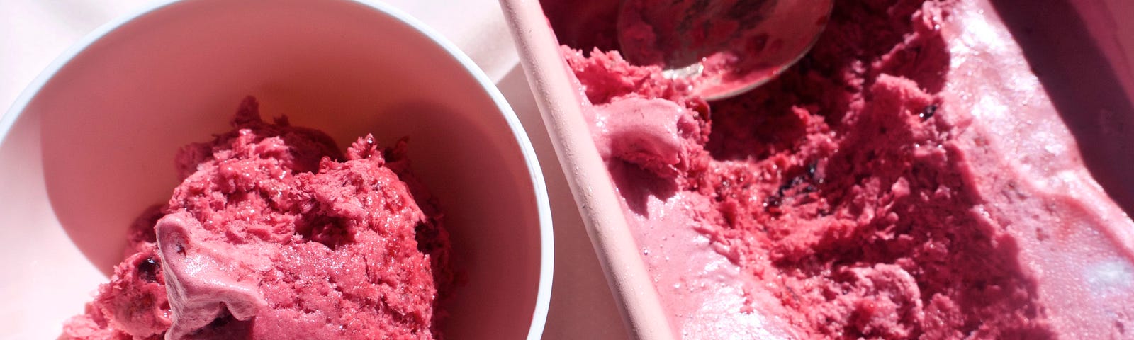 A fresh scoop of deep purple berry ice cream from a carton of the same rich looking ice cream.