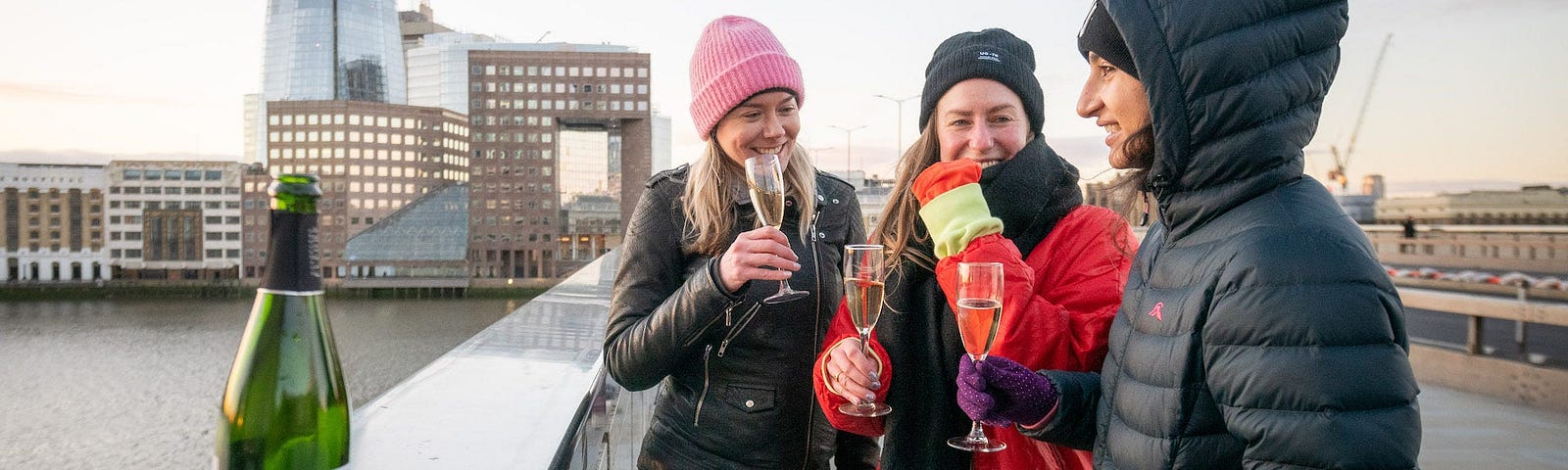 Friends enjoy a glass of Prosecco while watching the sunrise on London Bridge.