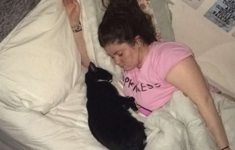 A photo of me lying in my bed asleep with my cat lying asleep very close to me facing me