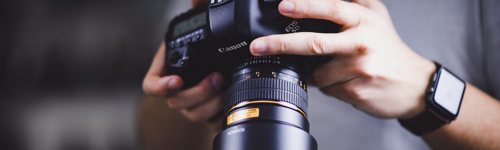 Man holding a camera and adjusting its settings on the back.