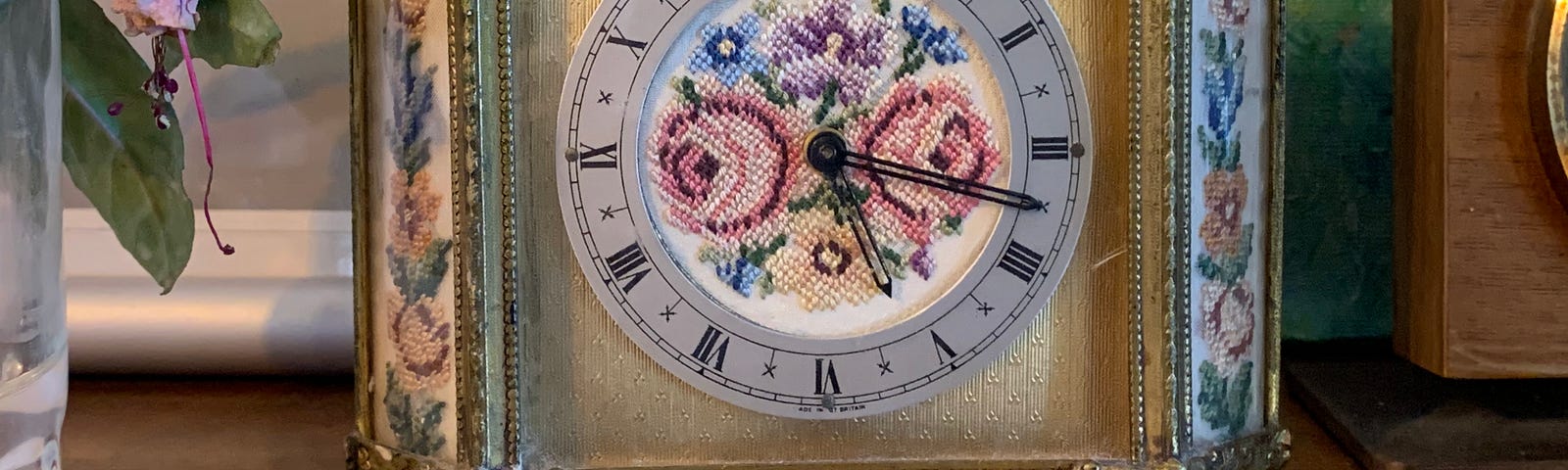 an old gilt clock, with a silk face embroidered with flowers, sat on a bookshelf.