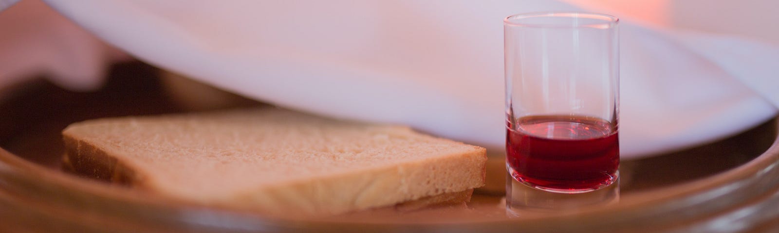 A photo of bread and wine on a plate.