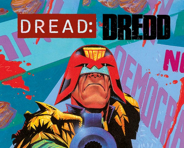 The cover of Dread: Dredd (spelled with d-r-e-d-d). Judge Dredd stands in the center of the image, pointing his lawgiver pistol at the camera with his right hand. He wears a red and black helmet that only shows his lower nose and mouth. The collar of his blue-black body suit can be seen, but the rest is obscured in shadow. You can clearly see the gold shoulder pads, the right side pad shaped like an eagle. He wears a green glove with armored knuckles.