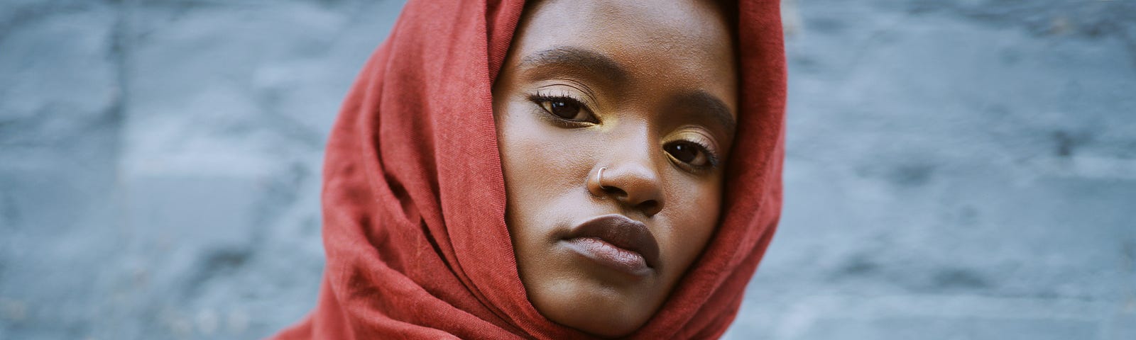 A woman wearing a red head wrap looks at the camera.