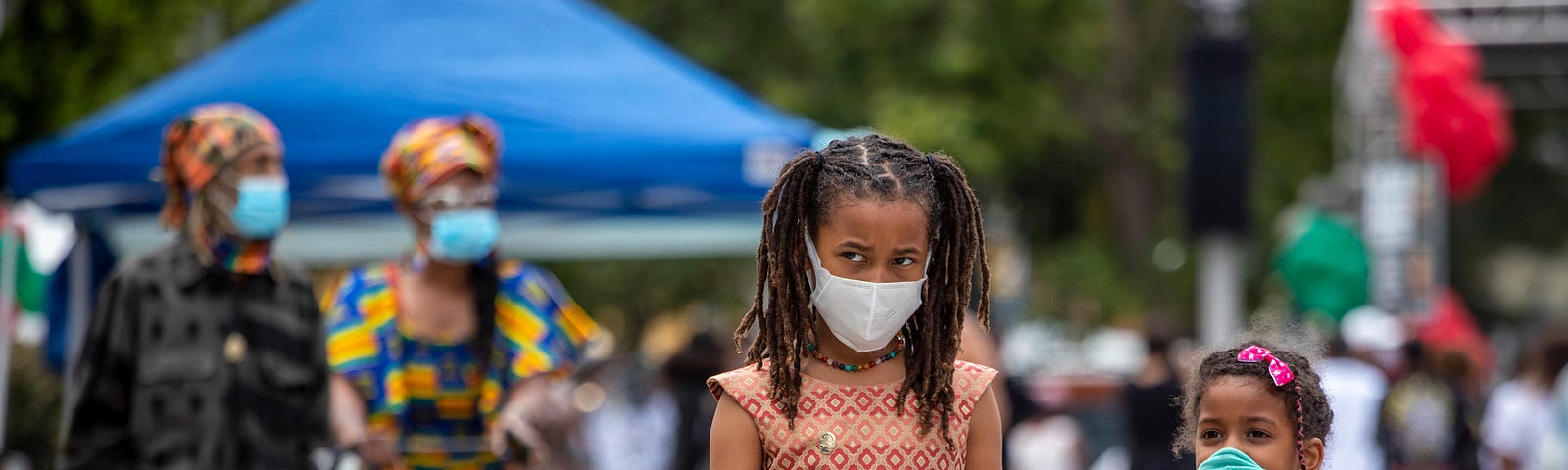 Two young African-American girls walk together, holding hands during the Leimert Park Rising Juneteenth celebration in LA.