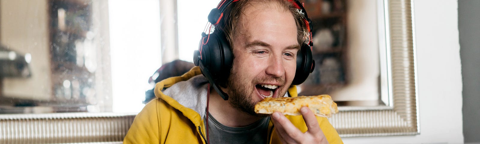 A photo of a man eating pizza and laughing while on a video call.