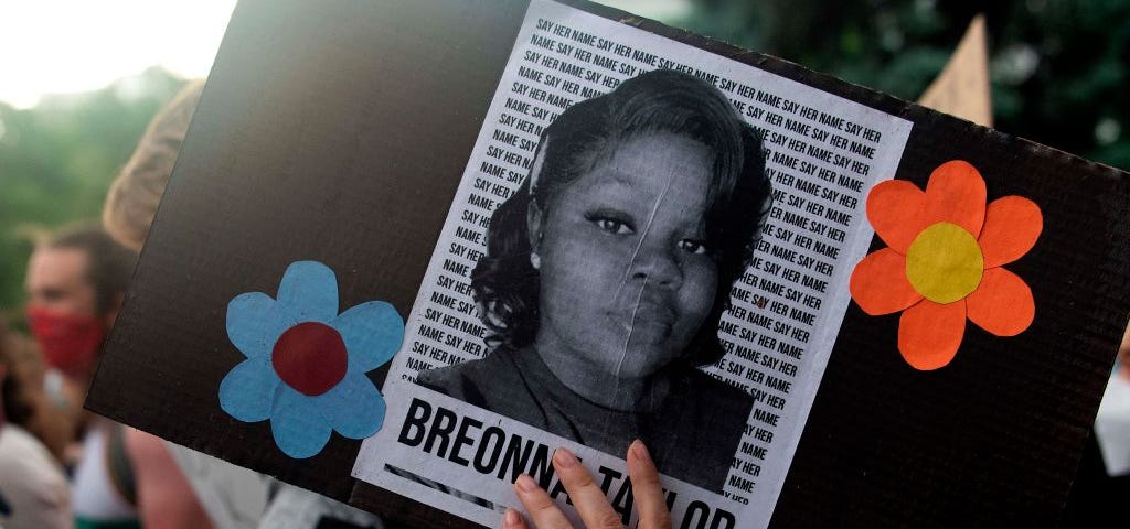 A photo of Breonna Taylor on a sign that a protestor is holding at a rally in Denver, Colorado.