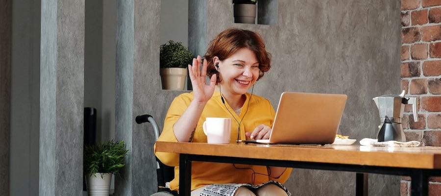 Lady waving during video chat session on her laptop