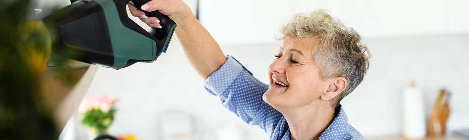 Woman cleaning her kitchen with a smile.