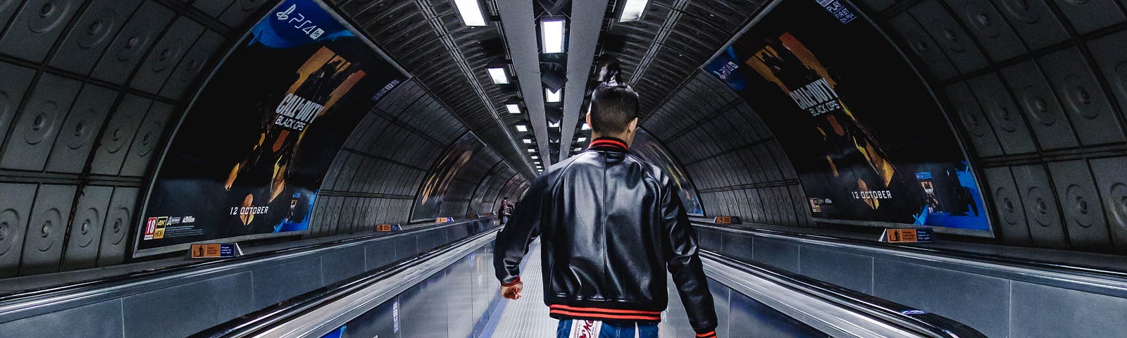 A man strides purposefully down a moving walkway at a subway stattio