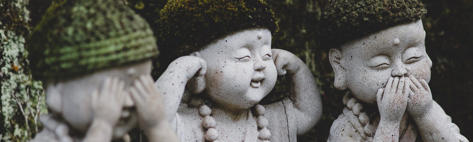 3 stone statues of Buddha-like children. One covers their eyes; one, their ears; and one, their mouth.