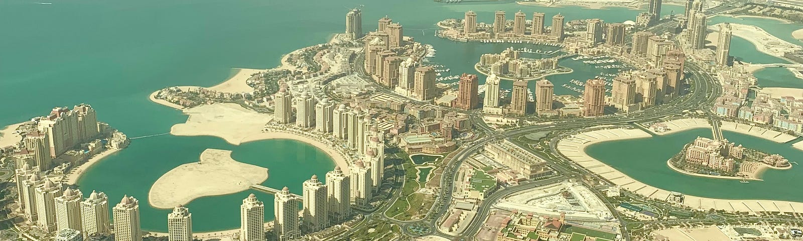 View of the city of Doha from an airplane window: the rich green water, & skyscrapers all around the island