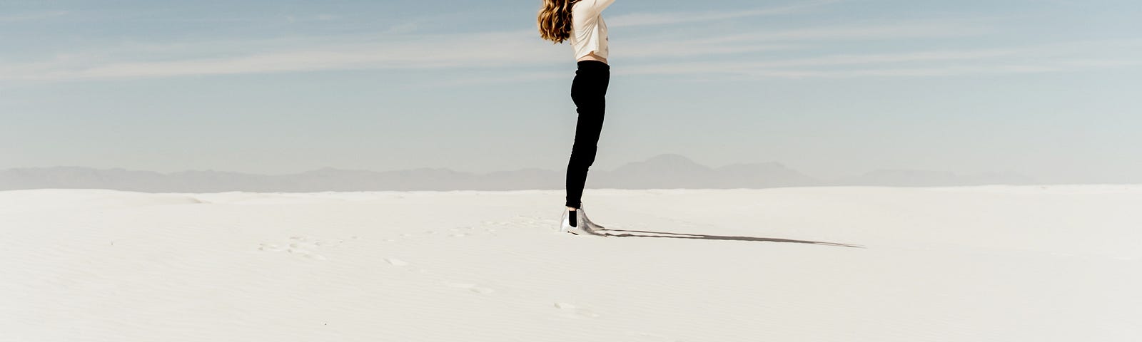 A woman standing on a white sand landscape.