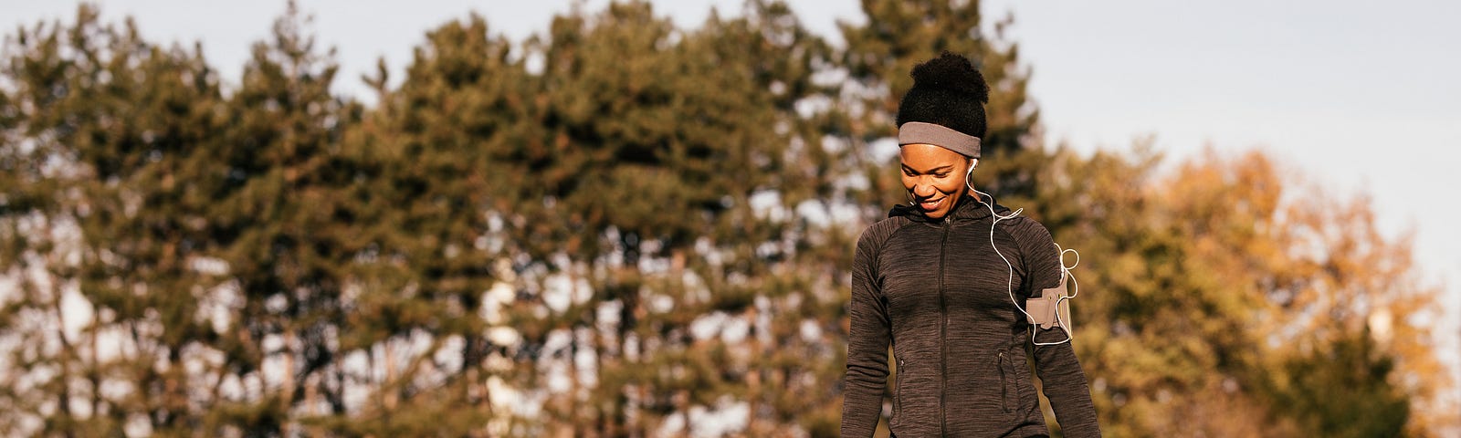 A photo of a black woman walking her dog at a park.