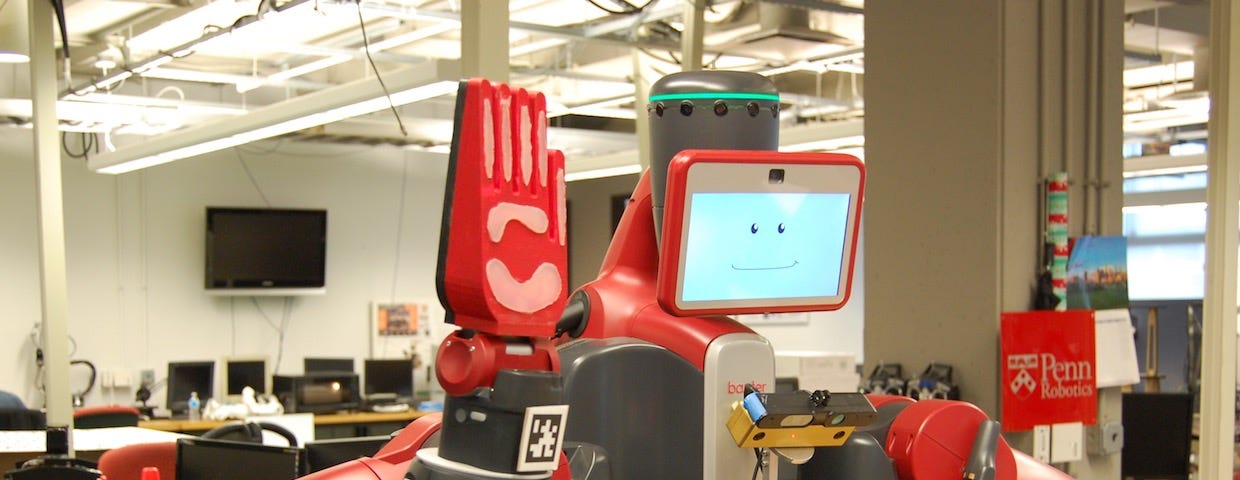 A red humanoid robot holds up its hand for a high-five. A smile is displayed on the screen that serves as its face.