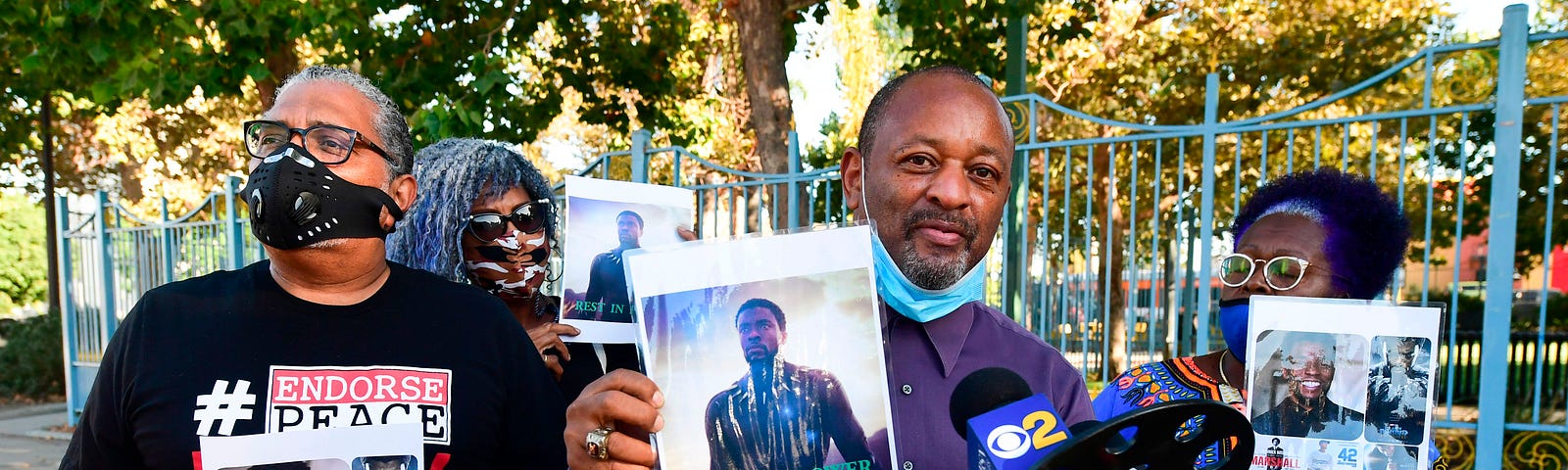 Photographs of the late actor and producer Chadwick Boseman are held during a vigil by fans.