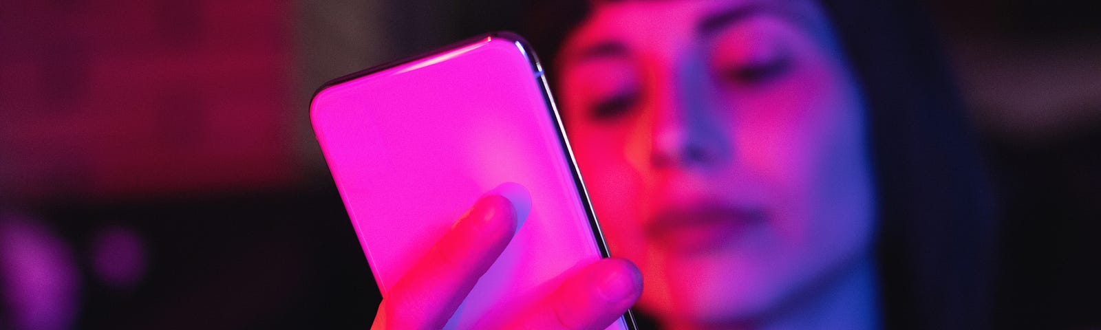 A neon photo of a young woman looking at her white smart phone.