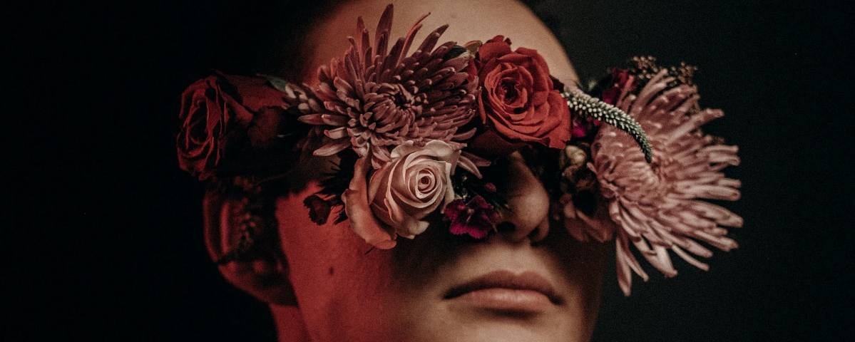 Photo of a man with his eyes covered by flowers.