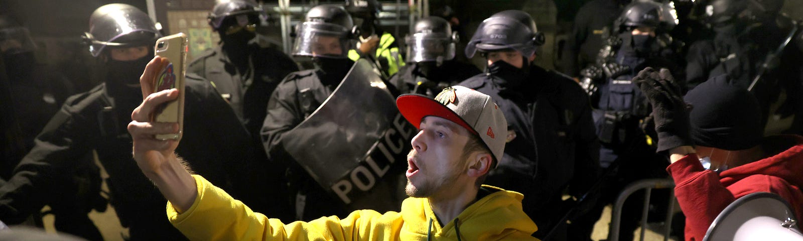 A man takes a selfie photo with police officers in riot gear