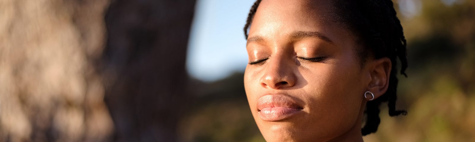 Close-up shot of healthy young woman meditating outdoors with her eyes closed.