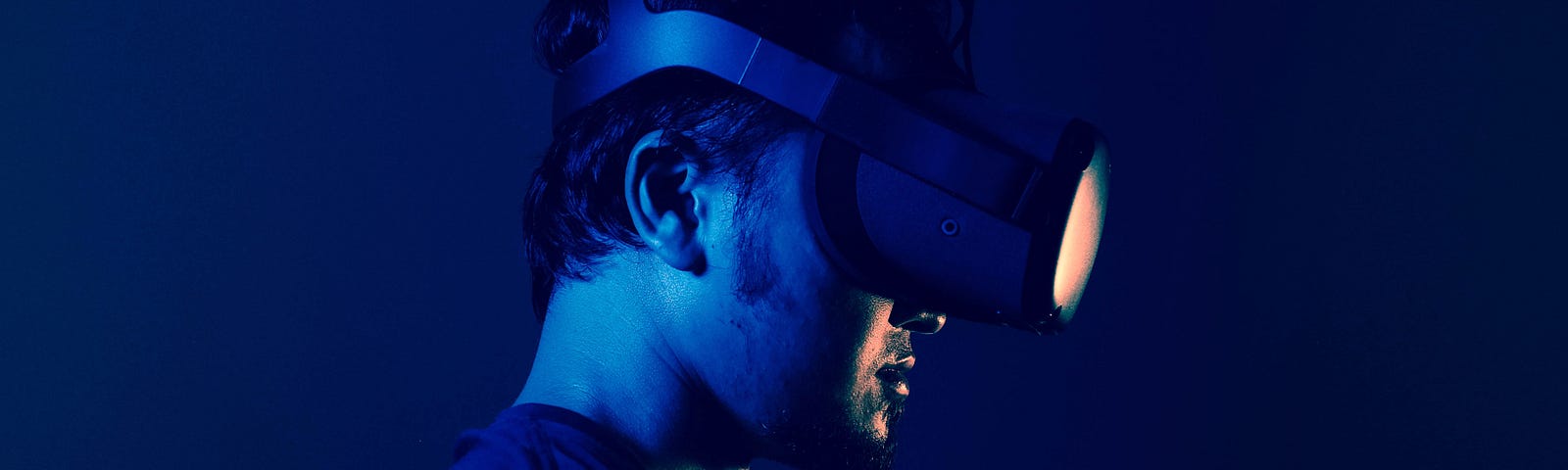 Stylish dark blue image of a man wearing Oculus headset.