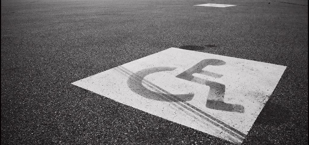 An accessible parking spot in an empty parking lot, in black and white.