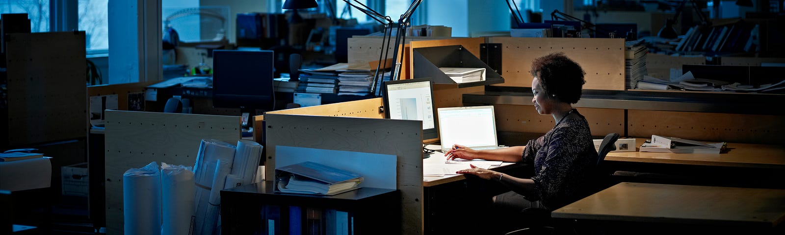 A black woman working alone in a dark office