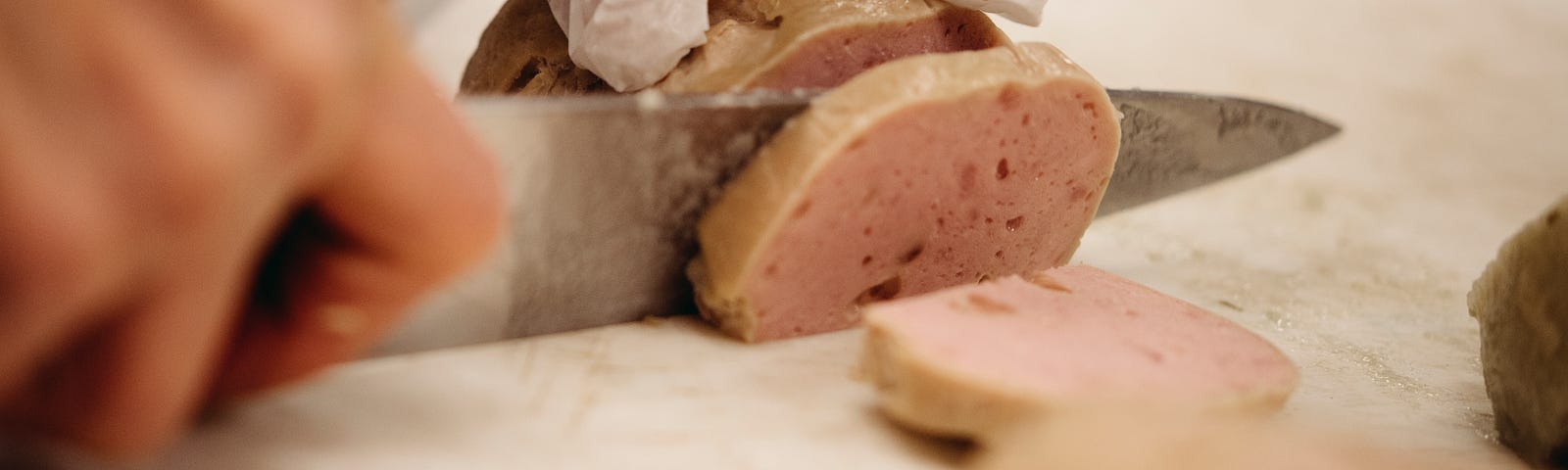 Closeup of a chef’s hands slicing chả lụa.