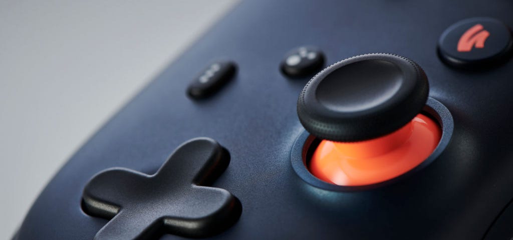 Very zoomed-in photo of a Google Stadia controller, the D-pad and analogue stick with orange highlight.