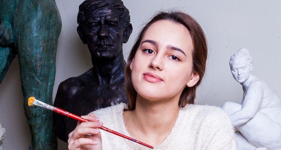 Young female artist with paintbrush and statues