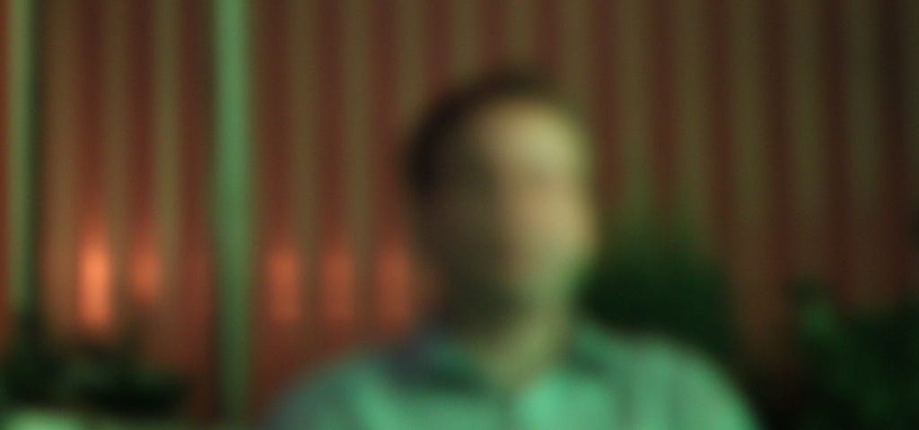 A blurred photo of a man in a presumed bar.