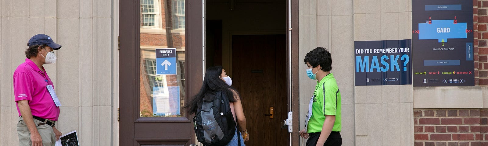 Safety ambassadors checking a student wearing a mask prior to entering a building at UNC-Chapel Hill.