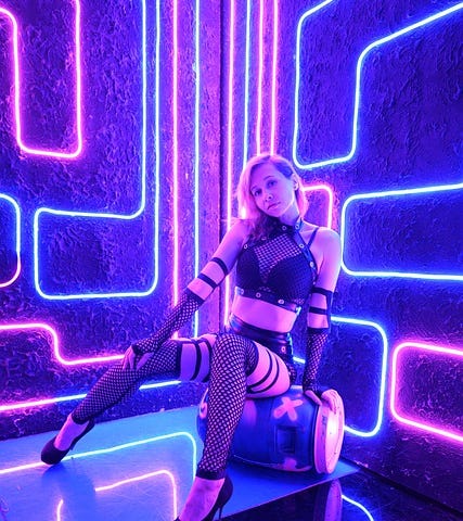 Woman, latex, fishnet, fetish gear, seated, straps and buckles, neon lights, sexy