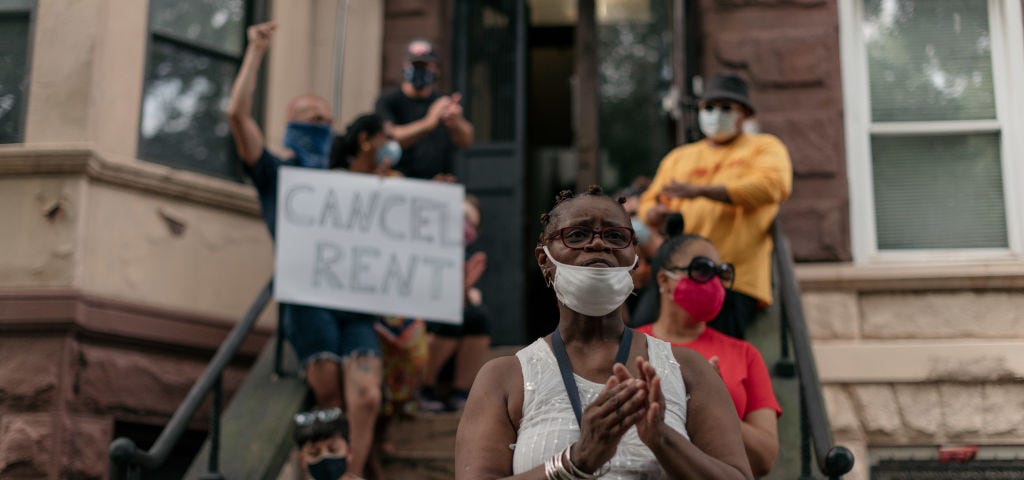 A group of housing activists in Brooklyn with a “cancel rent” sign. A Black woman stands in the front wearing a mask.