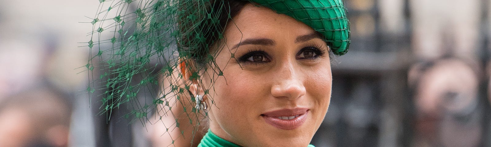 Meghan, Duchess of Sussex, at a public event wearing a green outfit with matching hat.