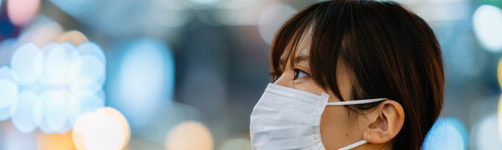 A portrait of a young woman wile wearing a face mask for protection from cold and flu and viruses.