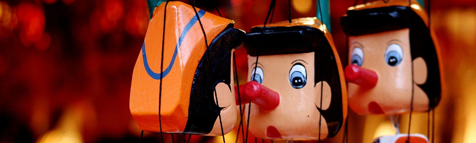 A close-up of 3 Pinocchio string puppets.