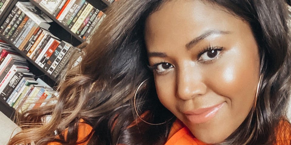 A selfie of Amerie with a bookshelf behind her.