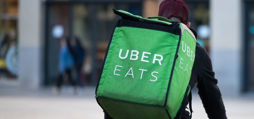 A Uber Eats courier rides a bike through the city center.