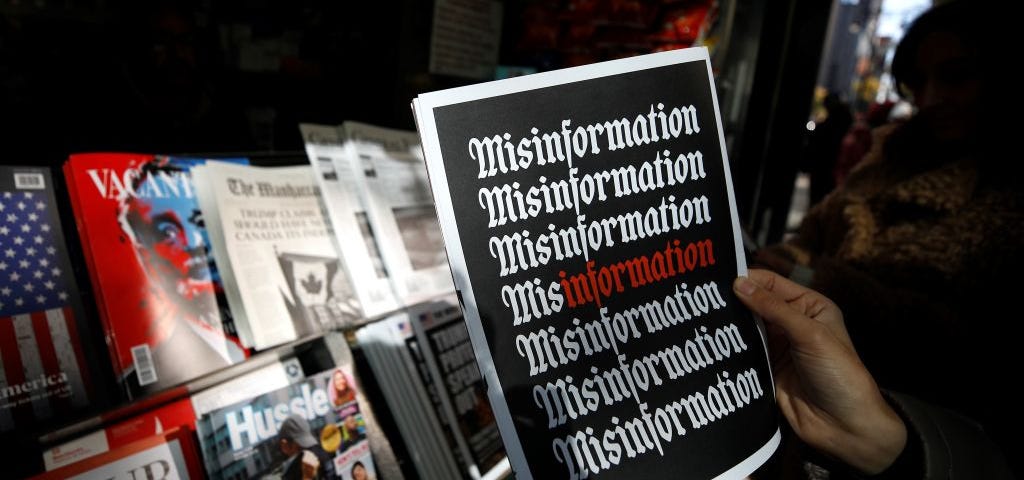 Misinformation newsstand in Manhattan. Person holds magazine that has “Misinformation” on the cover.