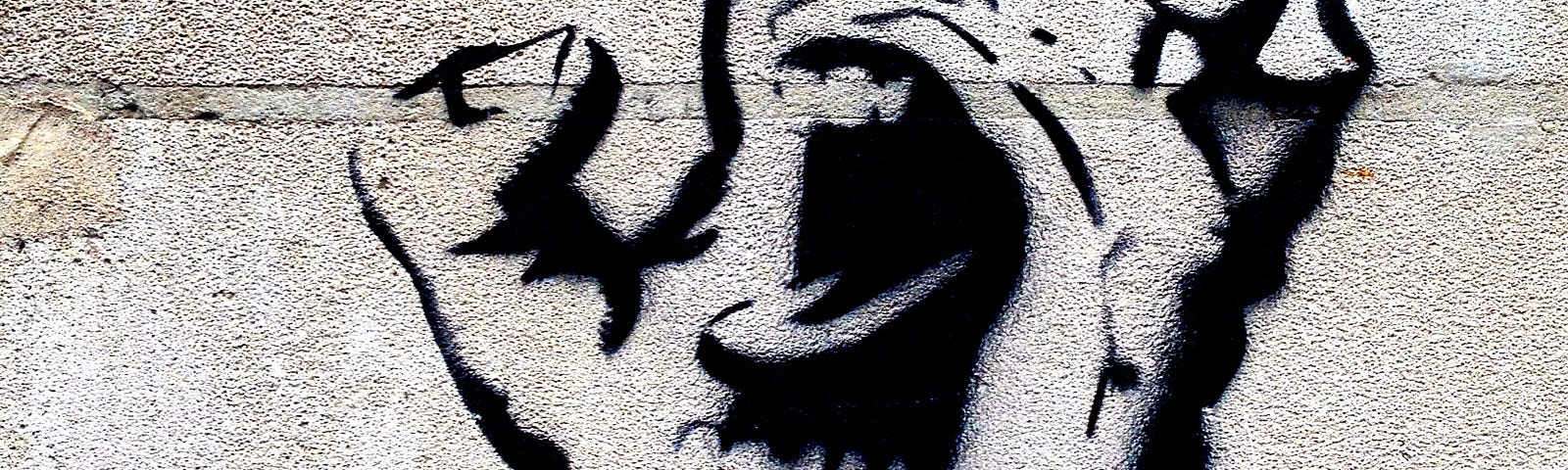 A graffiti drawing of a hand reaching out with an open mouth drawn on the palm.