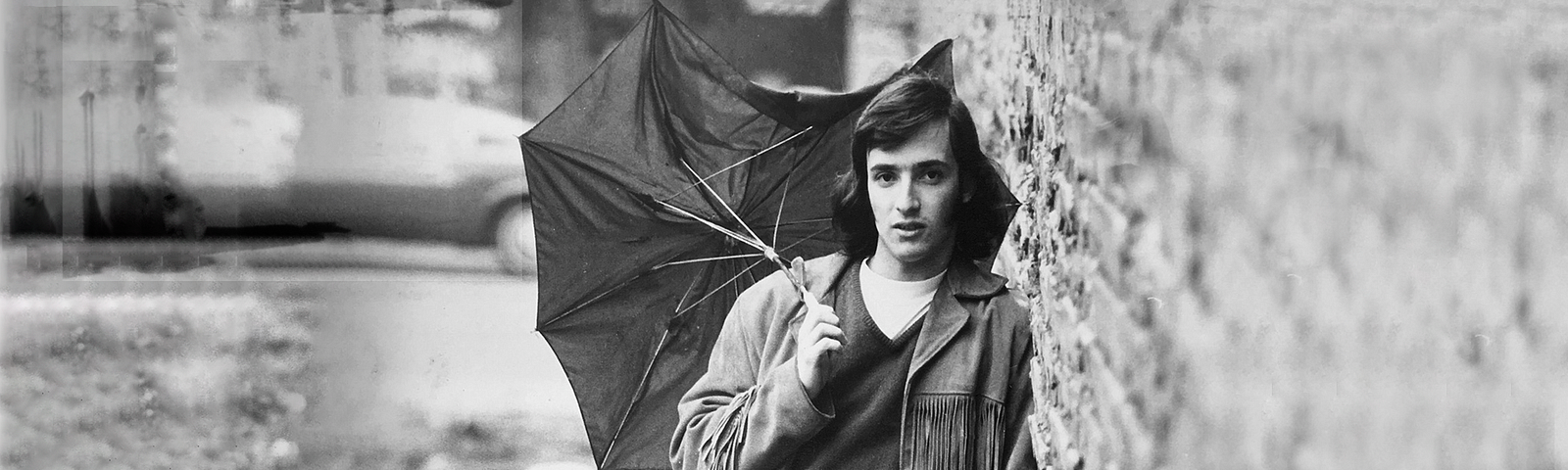 Teen boy standing holding a broken unbrella