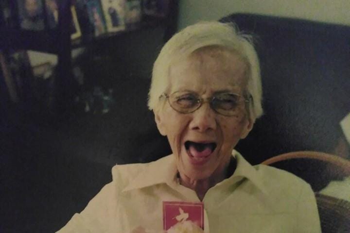 Picture of the Author’s maternal grandmother smiling as she holds a peeled mandarin orange and a red packet during Chinese New Year.