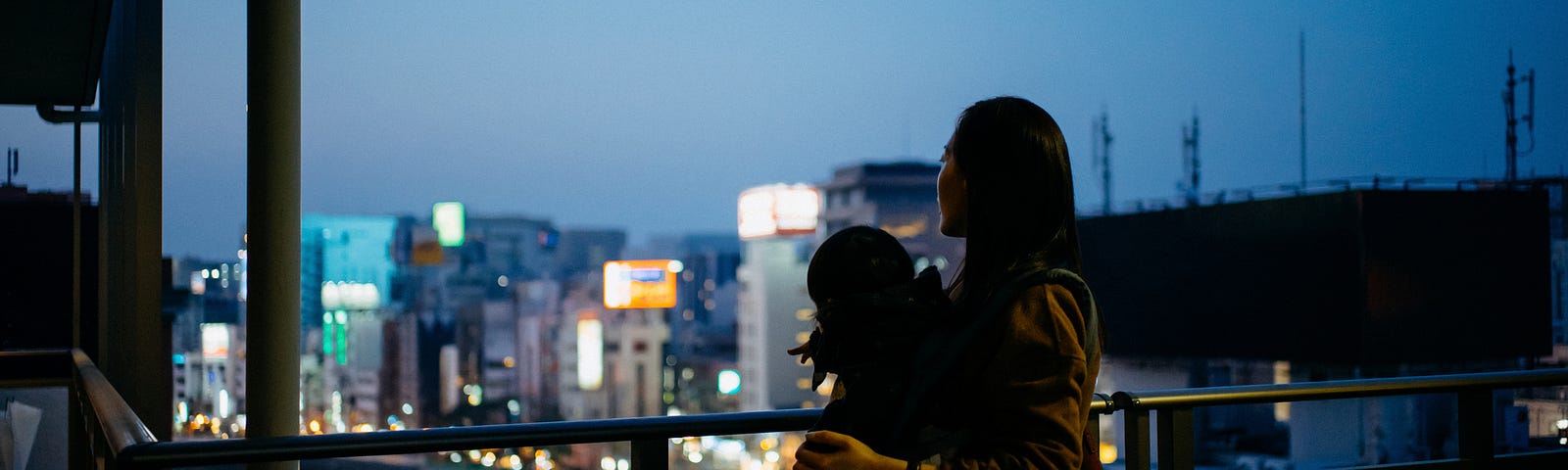 Mother with child looking out window at twilight.