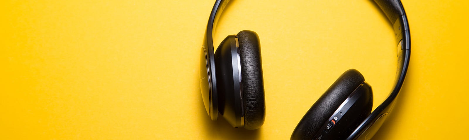 A pair of over the ear headphones on a yellow background