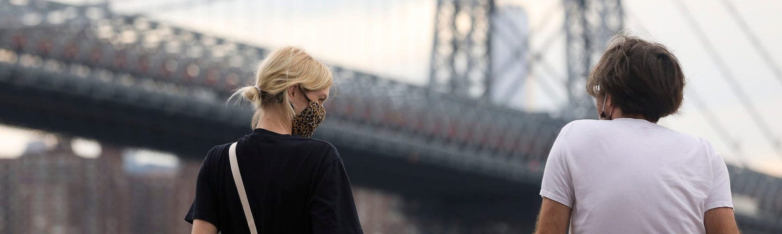 Individuals sitting by a bridge.