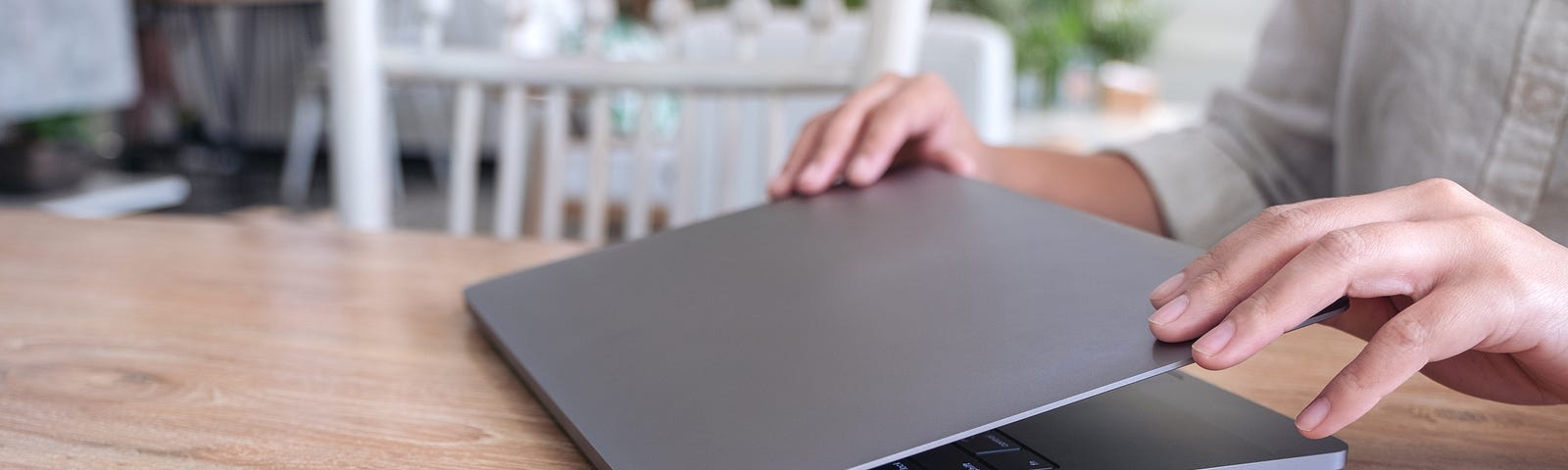 Person closing a dark gray Macbook.