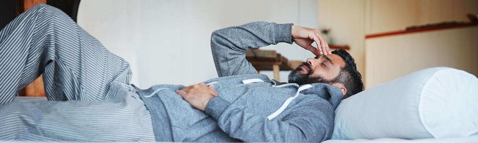 A photo of an exhausted man laying on a sofa/bed.