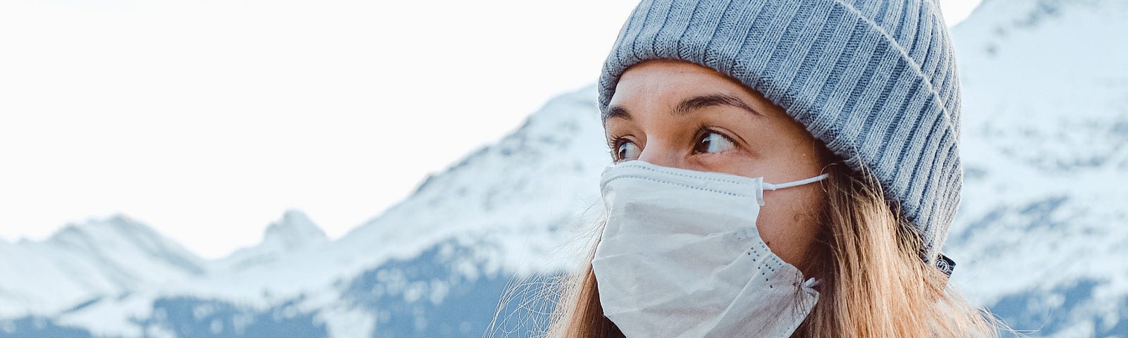 Woman wearing a mask outdoors with a snowy mountain behind her