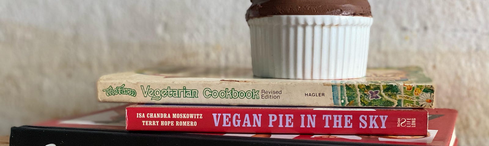 Ramekin of chocolate mousse on top of The Farm Vegetarian Cookbook, Vegan Pie in the Sky, Brooks Headley’s Fancy Desserts